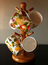 Close-up of cups hanging from wooden standing on table