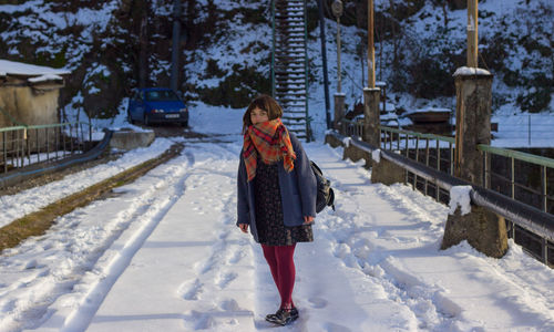 Rear view of woman walking on snow covered landscape