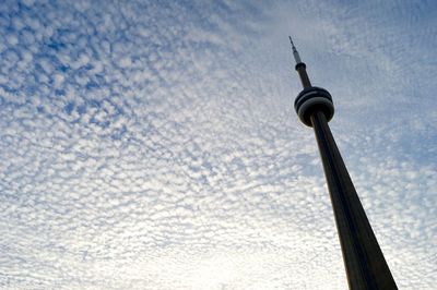 Low angle view of communications tower against cloudy sky