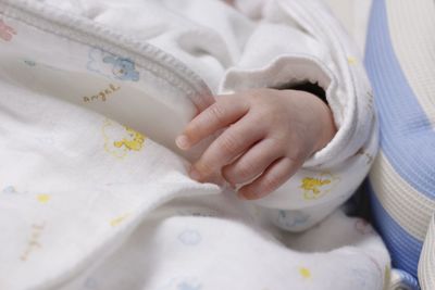 Midsection of baby lying on bed