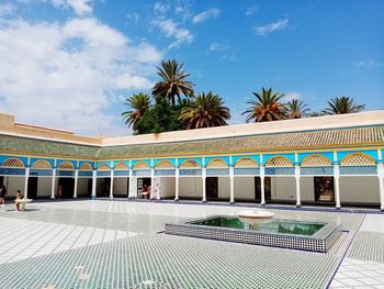 Palm trees by swimming pool against sky