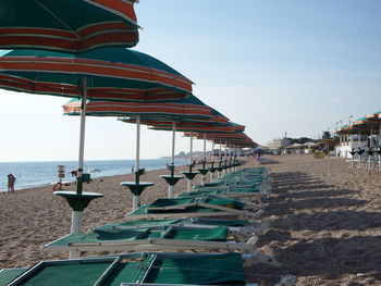 Deck chairs on beach against sky