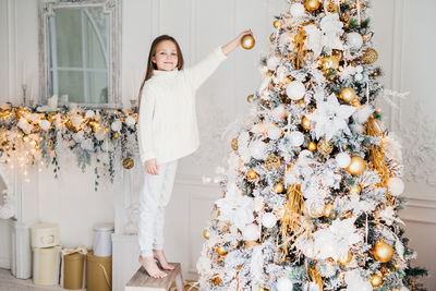 Portrait of woman standing by christmas tree at home