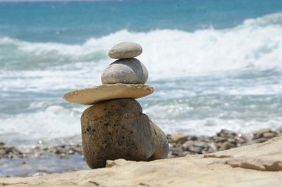 Close-up of stones stack on sand at beach against sea