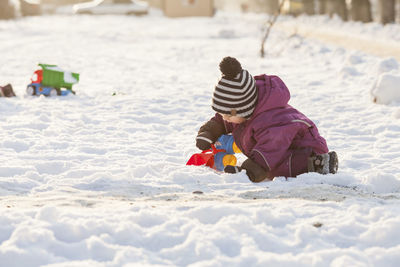 Rear view of girl playing on snow covered land