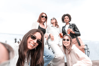 Happy group of women with sunglass, taking selfie with smartphone in sunny day. friendship concept.