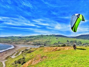 Woman with parachute on land against sky