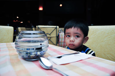 Cute boy sitting at table in restaurant