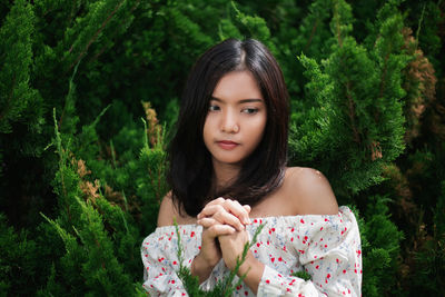 Thoughtful young woman standing against trees