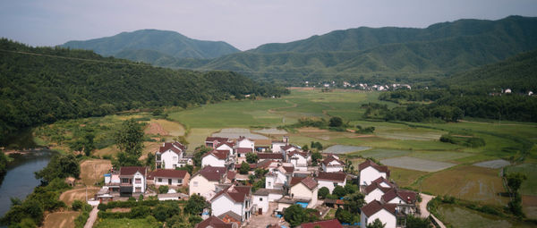 Houses on field by mountains against sky