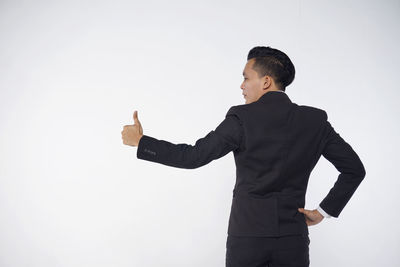 View of man with arms outstretched standing against white background