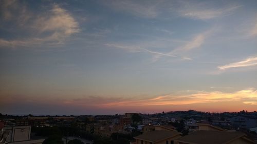 Houses in city against sky at sunset