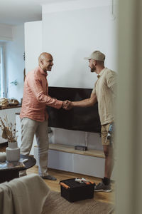 Mature male customer doing handshake with technician at home