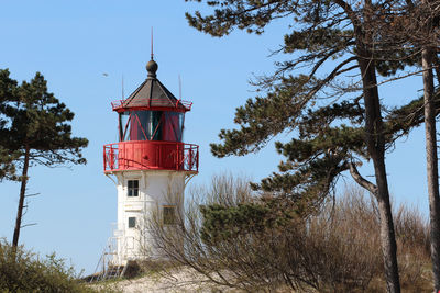 Low angle view of lighthouse amidst trees and buildings against sky