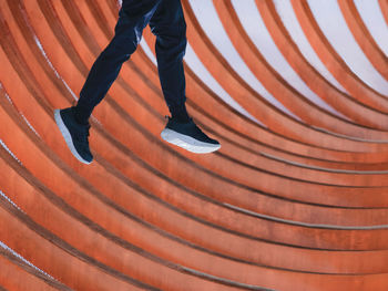 Close-up view of a boy jumping with orange curves background 