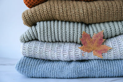 Stack of cozy knitted warm sweater with autumn fall maple leaf. sweaters in retro style. orange 