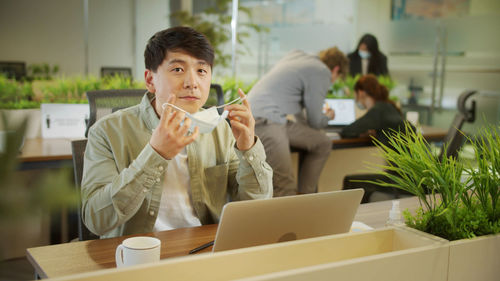 Portrait of businessman holding mask at office