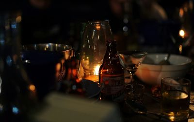 Lit candlelight with beer bottle and drinking glass on table
