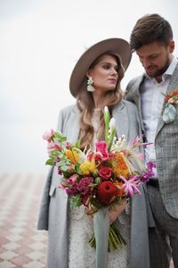 Newly married couple walking on pier over lake against cloudy sky