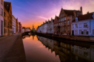 Canal amidst buildings against sky during sunset