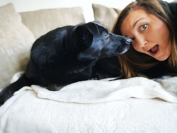 Portrait of young woman with dog on bed