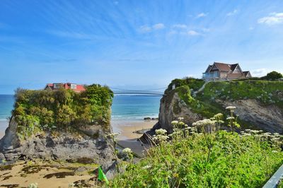 Houses on cliff by sea against sky