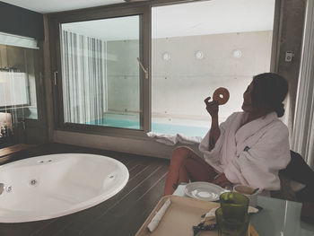 Woman holding food sitting at bathroom