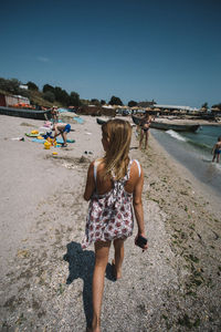 Rear view of women on beach against clear sky