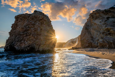 Rock formation in sea against sky during sunset