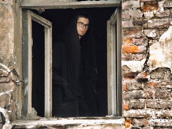 Man standing by window of abandoned building