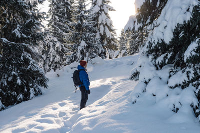 Man on a hike in the snow during winter, at sunset time.