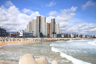 Sea by buildings against sky in city