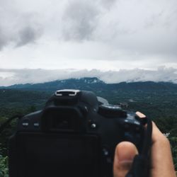 Midsection of man photographing on mountain against sky