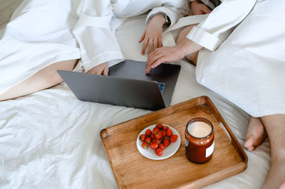 Couple watching movie on laptop. they are in bed in white bathrobes. breakfast, spa, aromatherapy