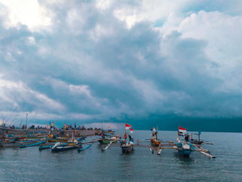 People on boats in sea against sky