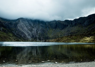 Scenic view of lake by mountains against sky