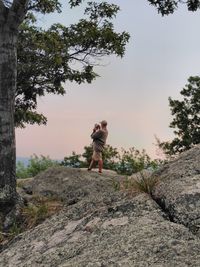 Man standing on rock against sky