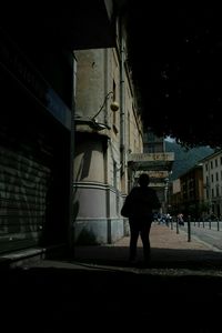 Rear view of woman walking on street against buildings at night