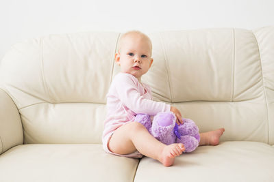 Cute baby girl sitting with toy at home