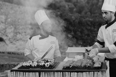 Chefs cooking food on barbeque grill at restaurant