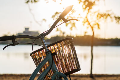 Close-up of bench by tree against lake during sunset