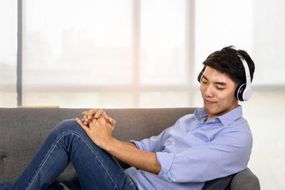 Side view of a young man sitting outdoors