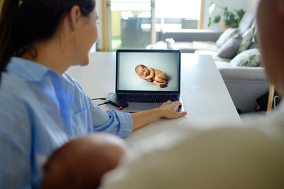 Side view of woman using laptop at home