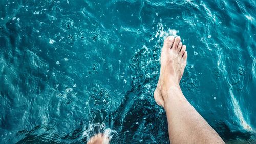 Low section of man splashing water at lake