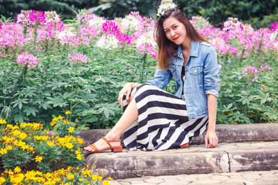 Full length of a smiling young woman against pink flowering plants
