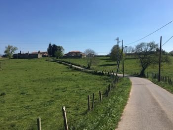 Road amidst field against clear sky