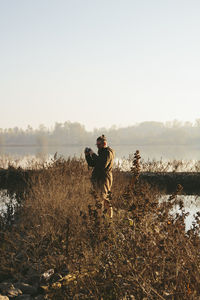 Man photographing through camera on field against sky