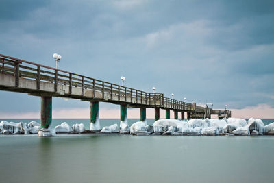 Low angle view of bridge over sea against cloudy sky