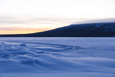 Scenic view of frozen lake against sky during sunset