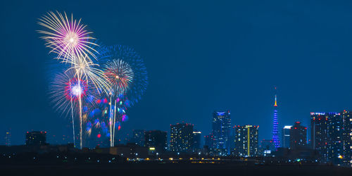 Illuminated tokyo tower and cityscape with fireworks display against sky at night